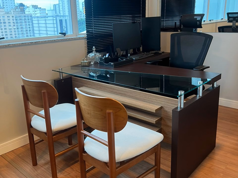 Sala de atendimento com mesa de vidro e cadeiras de madeira